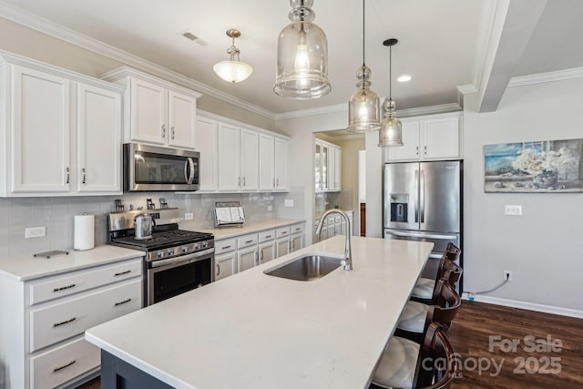 1426 Whitman Ct, York, SC 29745 - kitchen with appliances with stainless steel finishes, a kitchen island with sink, dark wood-style flooring, light countertops, and ornamental molding