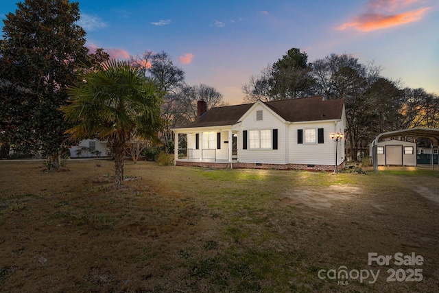 view of front facade featuring an outdoor structure, a yard, crawl space, a detached carport, and a chimney