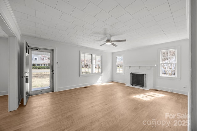 unfurnished living room featuring light wood finished floors, visible vents, baseboards, a ceiling fan, and a brick fireplace