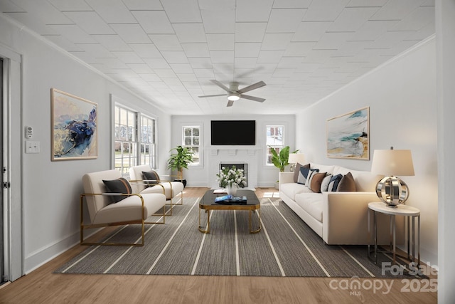 living area with ceiling fan, plenty of natural light, a fireplace, and wood finished floors