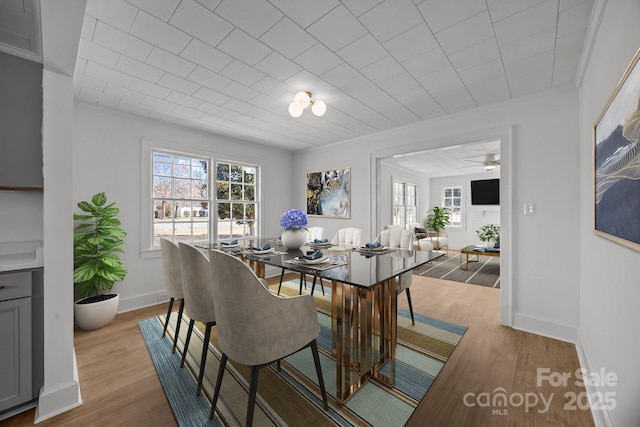 dining space with baseboards, ornamental molding, and wood finished floors