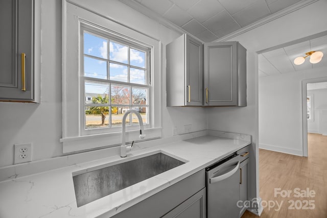 kitchen with light stone counters, dishwasher, a sink, and gray cabinetry