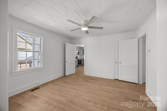 unfurnished bedroom with baseboards, light wood-style floors, visible vents, and crown molding