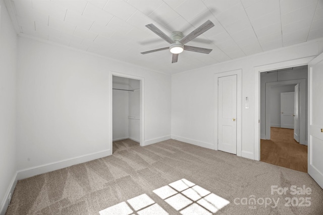 unfurnished bedroom with a closet, carpet flooring, ceiling fan, and baseboards