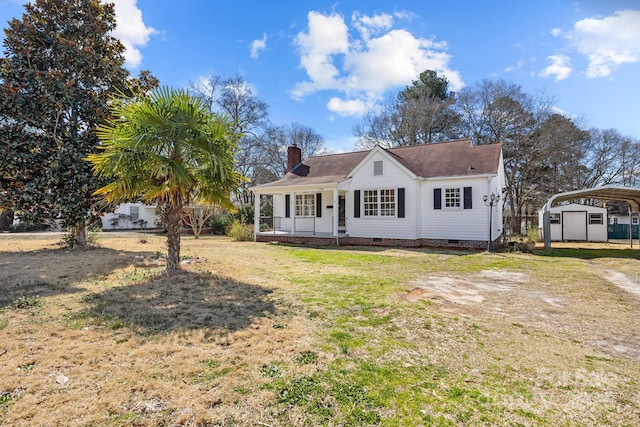 view of front facade featuring a chimney, a front yard, crawl space, a carport, and driveway