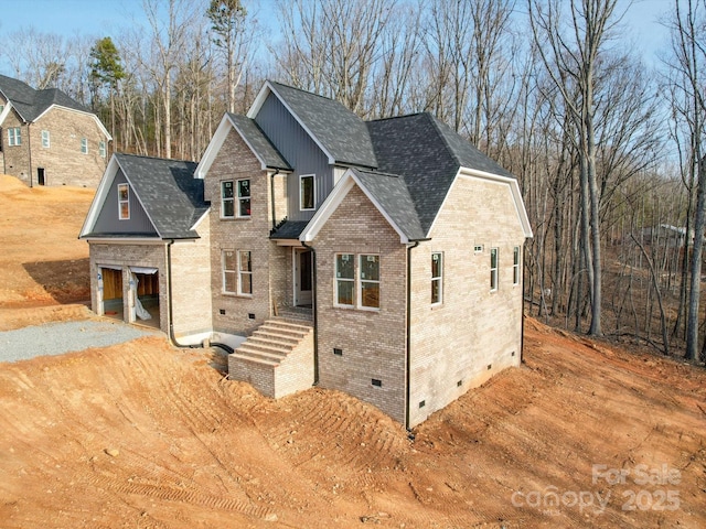 view of front of home with a shingled roof, crawl space, brick siding, and driveway