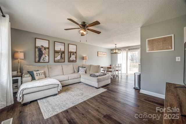 living room with dark wood-style flooring, visible vents, ceiling fan, a textured ceiling, and baseboards