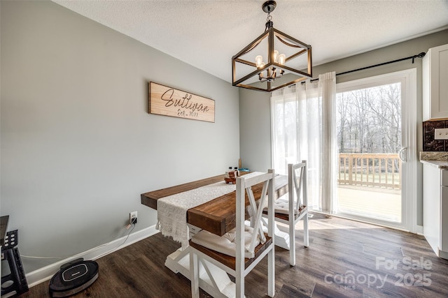 dining area featuring a textured ceiling, a chandelier, wood finished floors, and baseboards