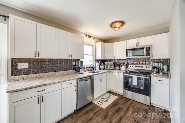 kitchen featuring tasteful backsplash, white cabinets, dark wood-style floors, appliances with stainless steel finishes, and a sink