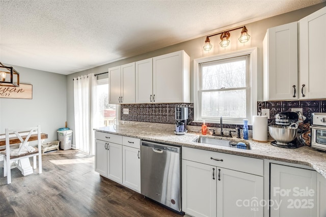 kitchen with backsplash, stainless steel dishwasher, dark wood-type flooring, white cabinetry, and a sink