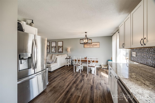 kitchen featuring a textured ceiling, a chandelier, light stone counters, dark wood-style flooring, and stainless steel fridge