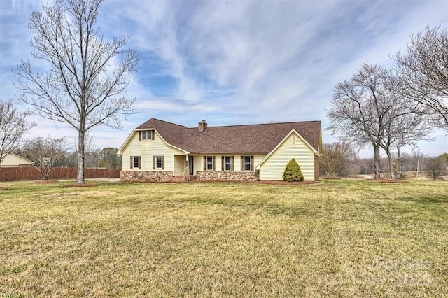 view of front of property featuring fence, stone siding, roof with shingles, a front lawn, and a chimney