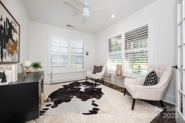 living area featuring baseboards, visible vents, and a ceiling fan