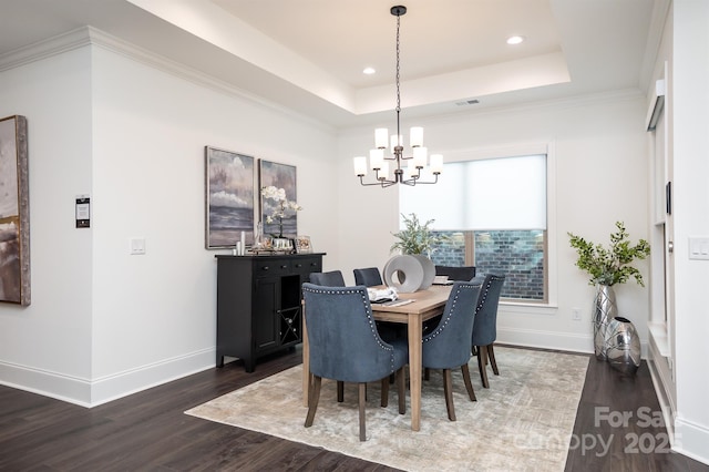 dining area featuring dark wood-style floors, a chandelier, a raised ceiling, and baseboards