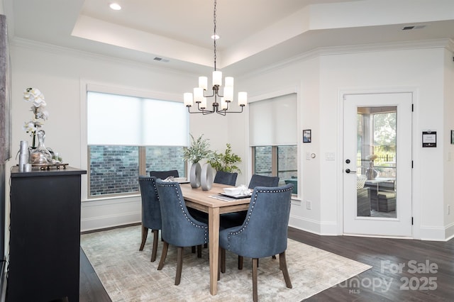 dining area featuring baseboards, visible vents, a raised ceiling, and wood finished floors