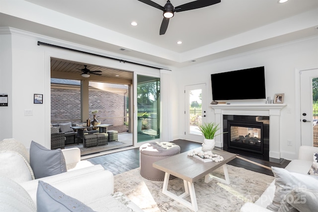 living area with recessed lighting, ceiling fan, a multi sided fireplace, and wood finished floors