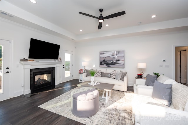 living room with recessed lighting, a multi sided fireplace, visible vents, dark wood-style floors, and a tray ceiling