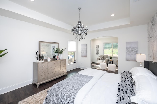 bedroom featuring dark wood-style floors, multiple windows, a raised ceiling, and baseboards