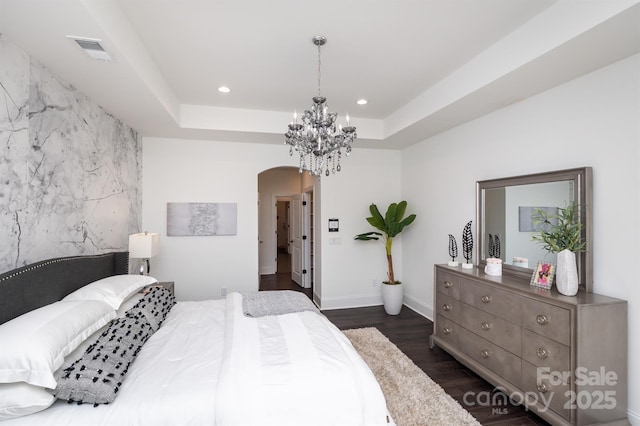 bedroom with visible vents, a raised ceiling, arched walkways, an accent wall, and recessed lighting