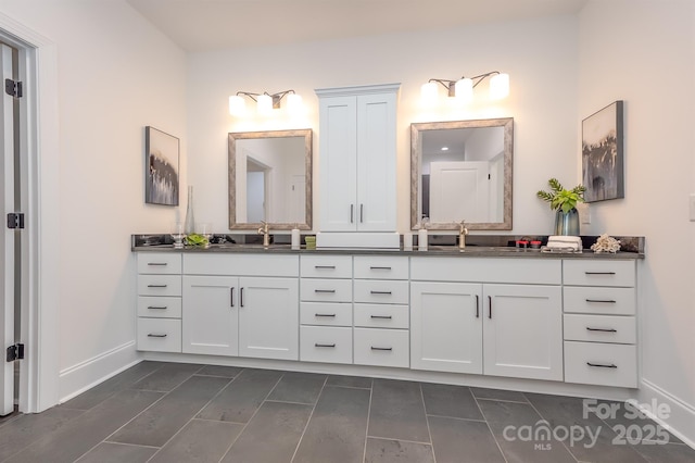 full bath with double vanity, baseboards, and a sink