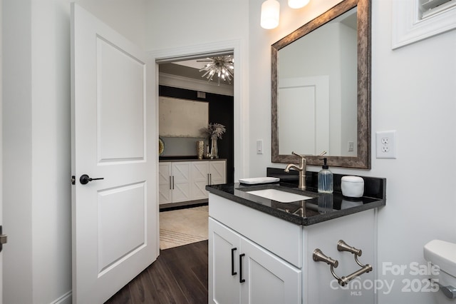 bathroom with toilet, crown molding, wood finished floors, and vanity