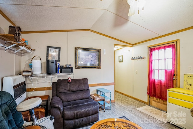 living area with heating unit, a ceiling fan, vaulted ceiling, a textured ceiling, and wood finished floors