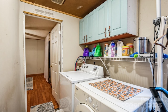 laundry area featuring cabinet space, visible vents, wood finished floors, and independent washer and dryer