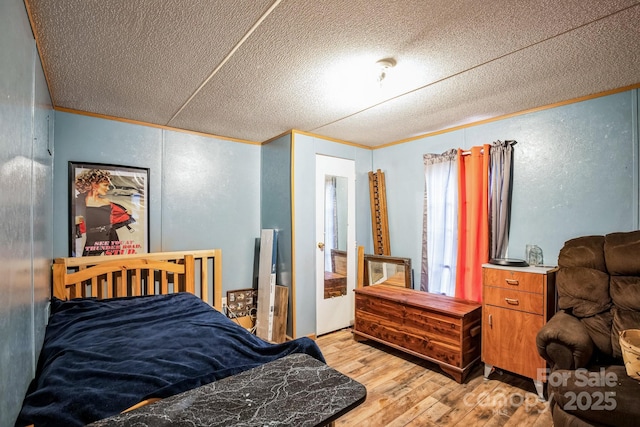 bedroom featuring light wood-style floors, a textured ceiling, and crown molding