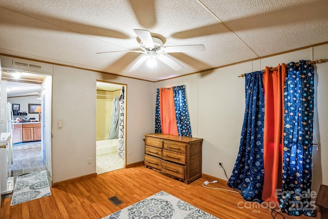 bedroom featuring a textured ceiling, visible vents, wood finished floors, and ornamental molding