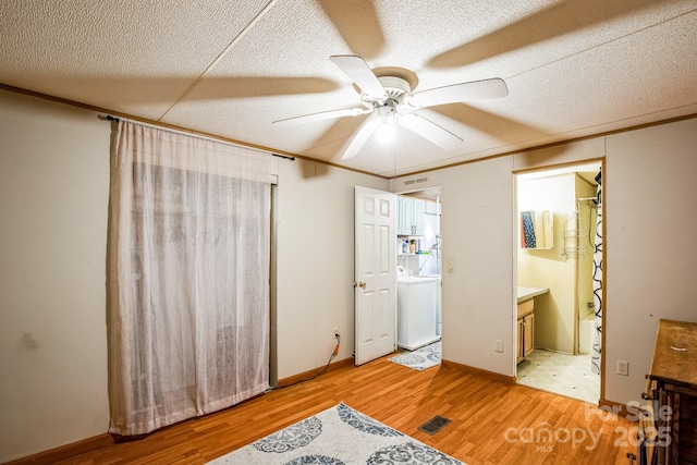 bedroom featuring light wood-type flooring, a textured ceiling, washer / clothes dryer, and crown molding