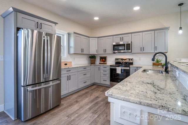 143 Carver St Unit 16, Brevard, NC 28712 - kitchen featuring stainless steel appliances, a sink, gray cabinets, light stone countertops, and wood finished floors
