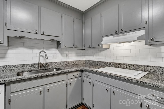 kitchen featuring decorative backsplash, under cabinet range hood, white cooktop, a sink, and gray cabinets