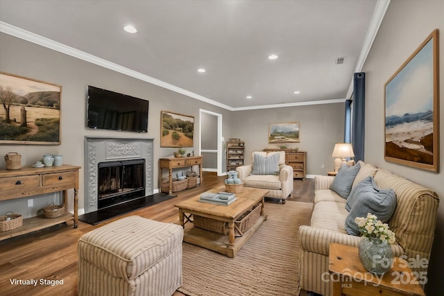 living room with crown molding, a tiled fireplace, wood finished floors, visible vents, and recessed lighting
