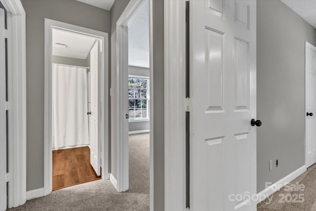 hall featuring baseboards and carpet