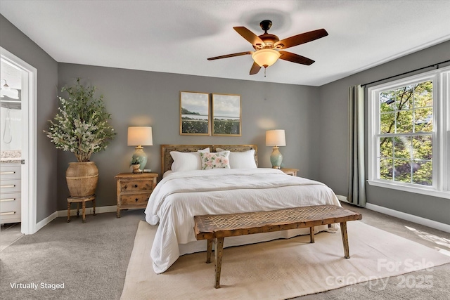 bedroom featuring connected bathroom, baseboards, light colored carpet, and ceiling fan