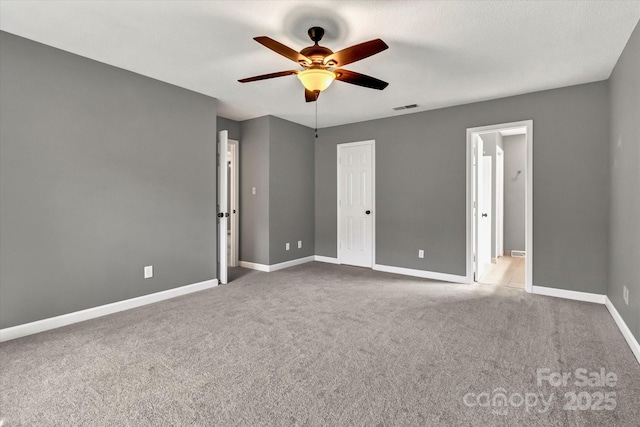 unfurnished bedroom featuring visible vents, baseboards, a ceiling fan, ensuite bath, and carpet floors