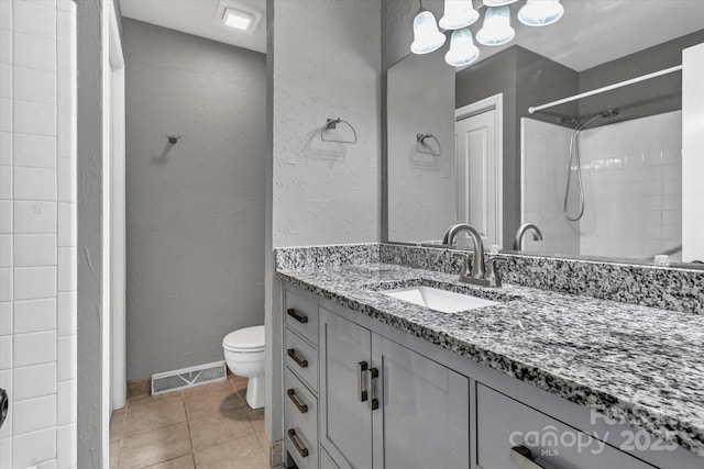 bathroom with toilet, vanity, tile patterned flooring, visible vents, and a textured wall