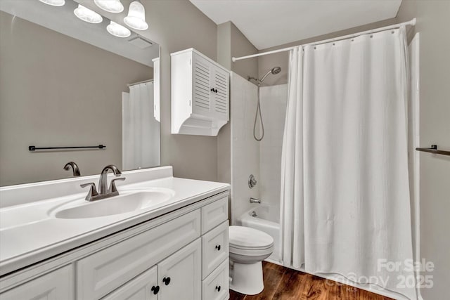 bathroom with vanity, toilet, visible vents, shower / bath combo with shower curtain, and wood finished floors
