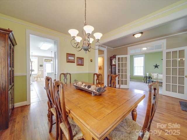 dining room featuring french doors, ornamental molding, wood finished floors, and baseboards