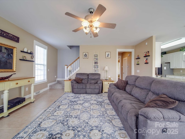 tiled living area with a ceiling fan, visible vents, stairway, and baseboards