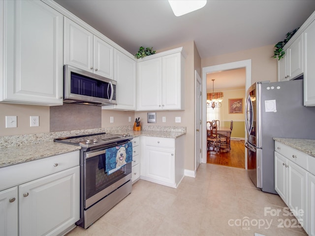 kitchen featuring an inviting chandelier, white cabinetry, stainless steel appliances, and light stone counters