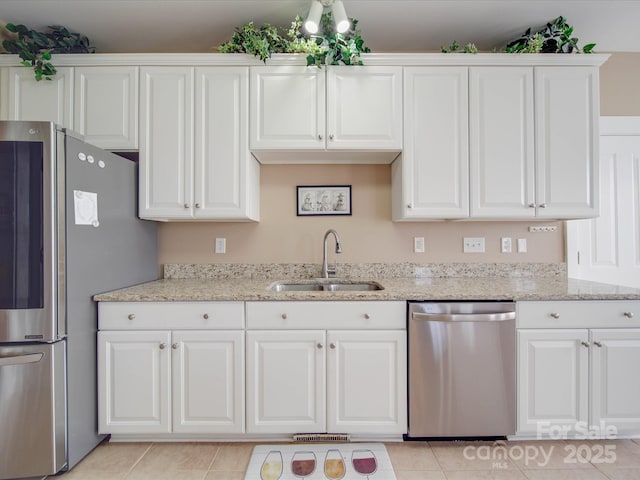 kitchen featuring stainless steel appliances, a sink, white cabinetry, and light stone countertops