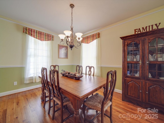 dining area featuring ornamental molding, a chandelier, light wood-style flooring, and baseboards