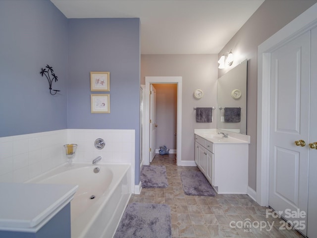 full bath with vanity, baseboards, and a bath