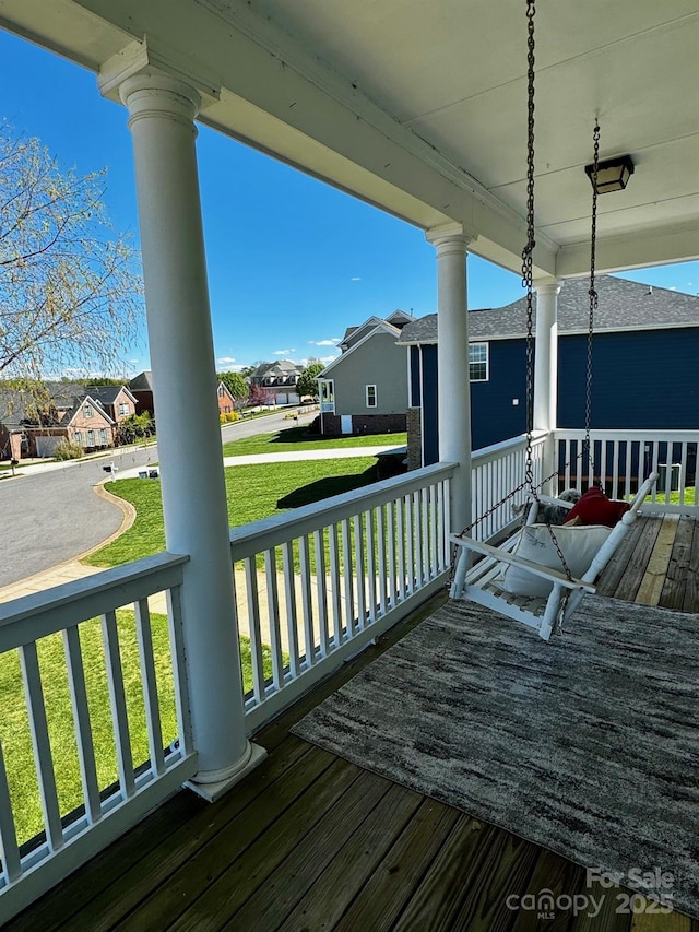 wooden terrace with a yard, a porch, and a residential view