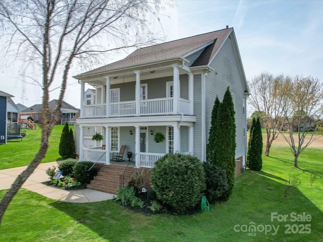 view of front of property with a front yard, covered porch, and a balcony