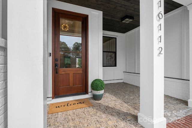 entrance to property with a porch, board and batten siding, and brick siding