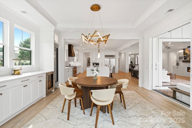 dining space with wine cooler, light wood-style flooring, visible vents, and crown molding