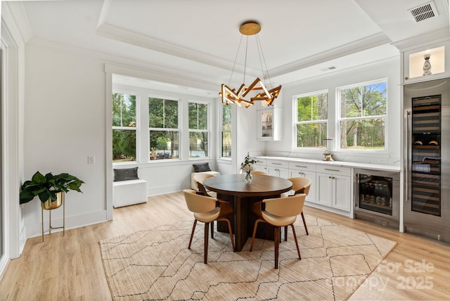 dining area with ornamental molding, wine cooler, visible vents, and a tray ceiling