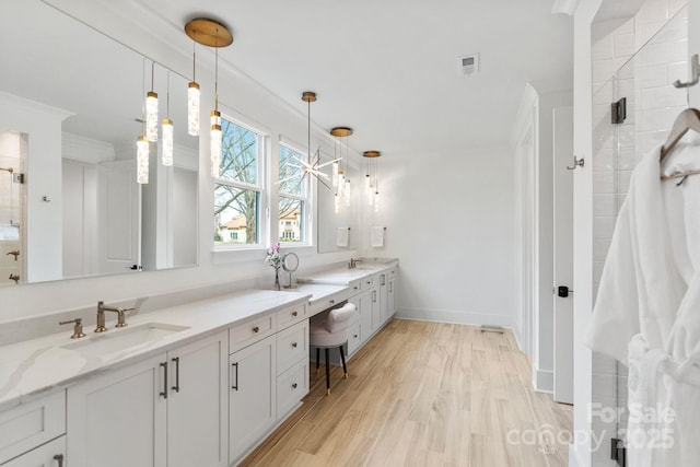 bathroom with a tile shower, double vanity, wood finished floors, and a sink